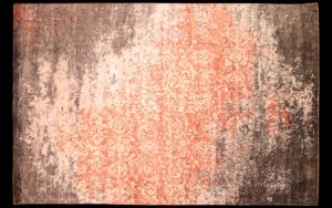 Dettaglio di tappeto moderno corallo, crema e marrone scuro effetto vissuto