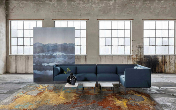 Tappeto moderno astratto grigio, oro e arancione in un ambiente industriale