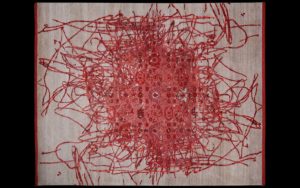 Dettaglio di tappeto moderno grigio e rosso con linee astratte e motivo centrale