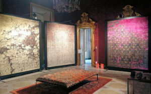 Tre tappeti moderni artistici nei toni crema, rosa e rosso esposti in un interno elegante